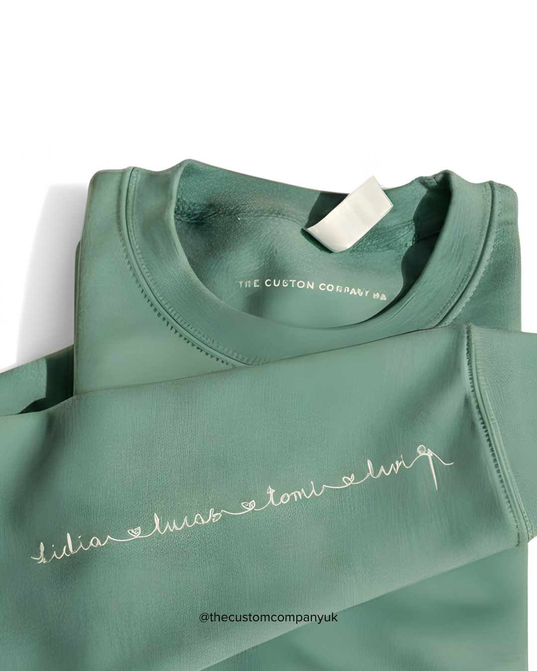 A detailed view of the sweatshirt sleeve where several names are written in a fine, cursive font, connected by a single, continuous line of thread, symbolizing a family bond.