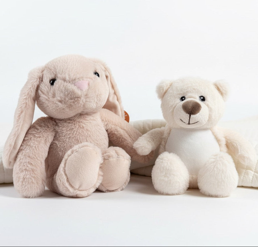 Two plush toys, a rabbit and a bear, sitting on a white surface with a white background.