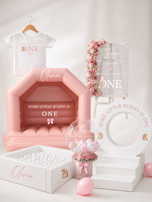 Personalised first birthday setup with blush pink soft play house, acrylic birthday sign, custom balloon display and white ball pit in a soft neutral lifestyle setting. Luxury bunny themed birthday decor for girls.