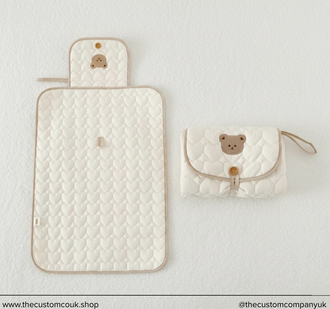 Luxury quilted nappy changing mat with embroidered teddy bear design, baby changing accessory.