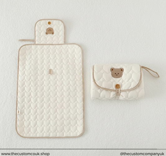 Luxury quilted nappy changing mat with embroidered teddy bear design, baby changing accessory.