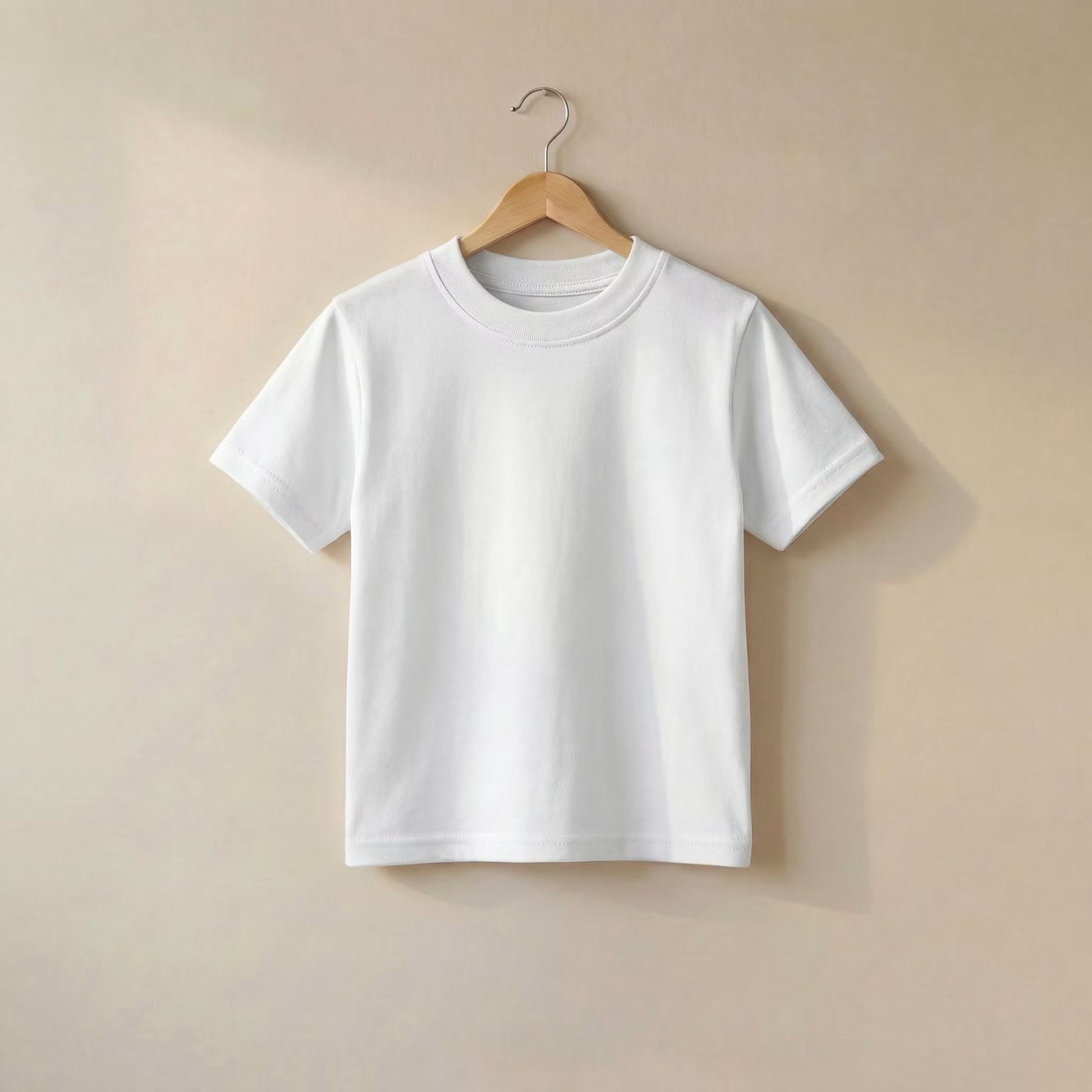 A plain white short-sleeve crewneck T-shirt hanging on a wooden hanger against a warm beige wall.