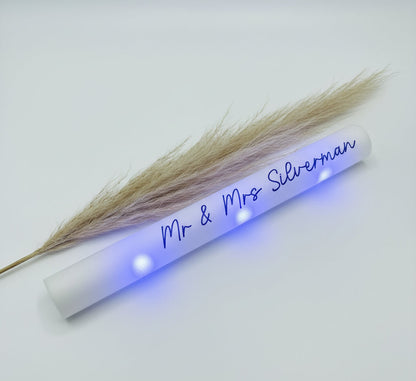 White tube with 'Mr & Mrs Silverman' text and dried pampas grass on a white background