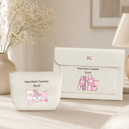 A white zippered pouch and matching envelope-style pouch set with pink illustrations and the text 'Important Teacher Stuff' and 'RC', styled on a tabletop with a vase of baby's breath and a lamp in the background.