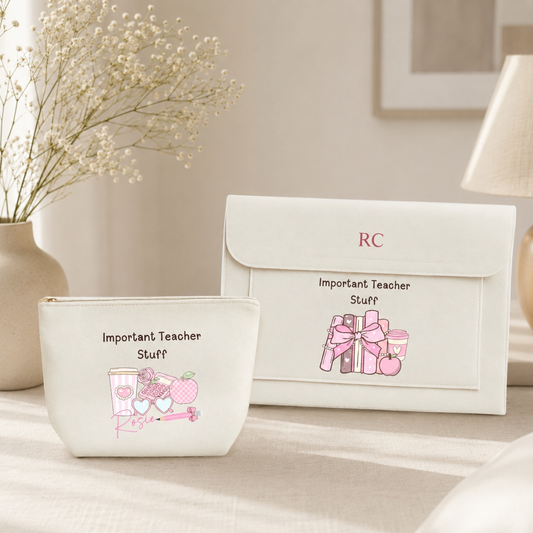 A white zippered pouch and matching envelope-style pouch set with pink illustrations and the text 'Important Teacher Stuff' and 'RC', styled on a tabletop with a vase of baby's breath and a lamp in the background.